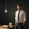Asad Raza stands confidently in a shirt and tie, next to a desk with a lamp. – Ghar.ie property listing