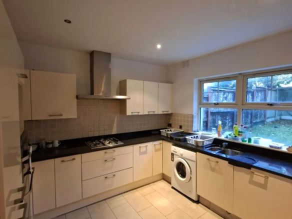 Modern kitchen with cream cabinets, black countertops, and stainless steel hood.