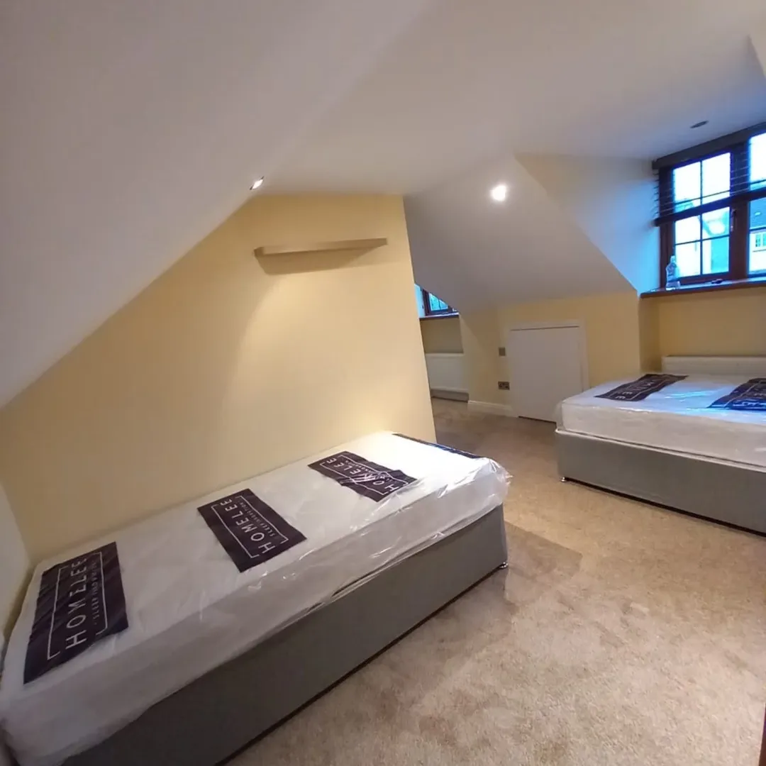 Attic Room Single Beds Sloped Ceiling Attic room with two single beds, yellow walls, sloped ceiling, and window.