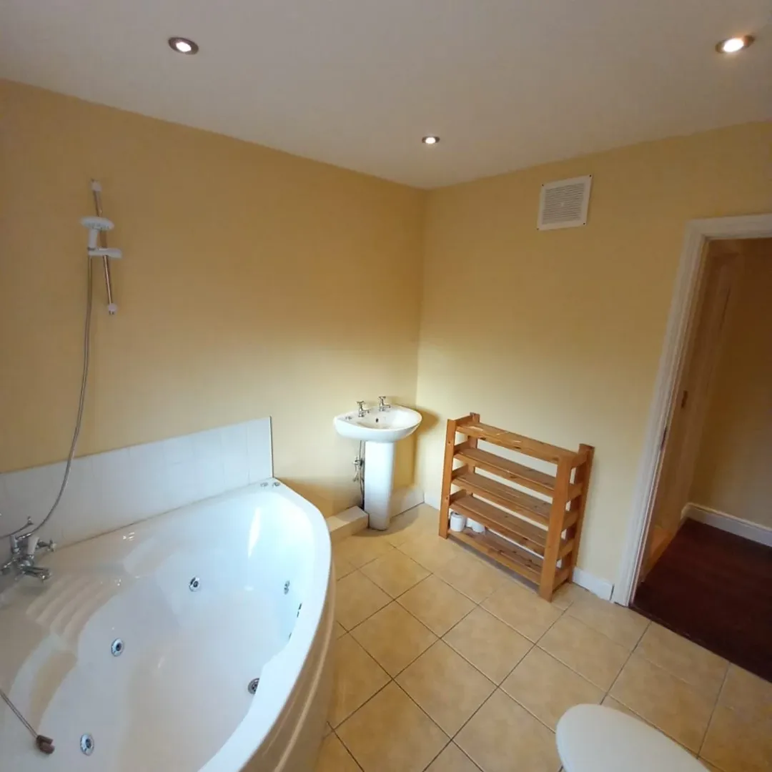 Bathroom Jacuzzi Tub Pedestal Sink Shelf Bathroom interior with jacuzzi tub, pedestal sink, and wooden shelf.