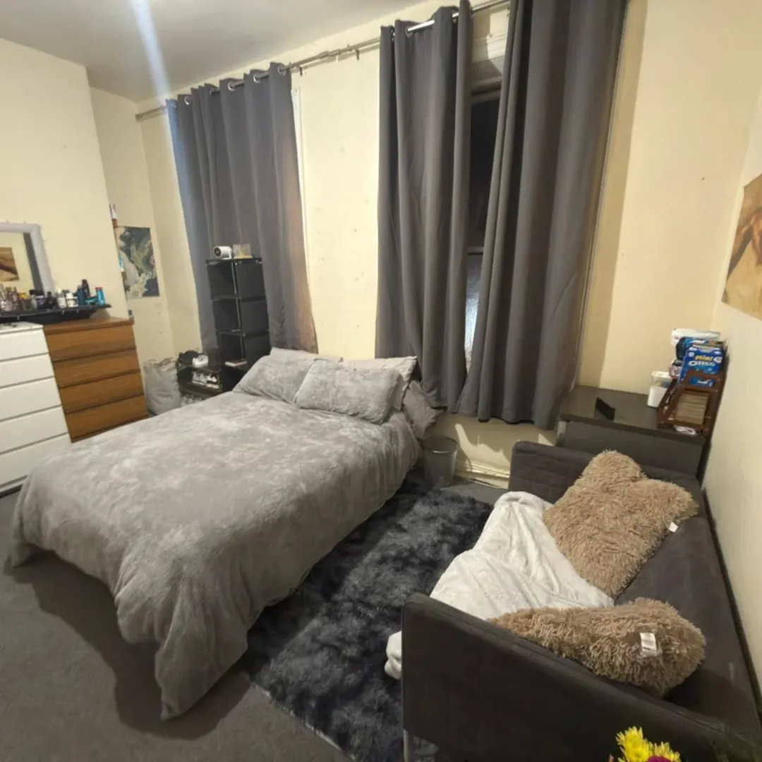 Bedroom Bed Futon Gray Curtains Cozy bedroom with bed, futon, gray curtains, and dark gray rug. Neutral wall color.