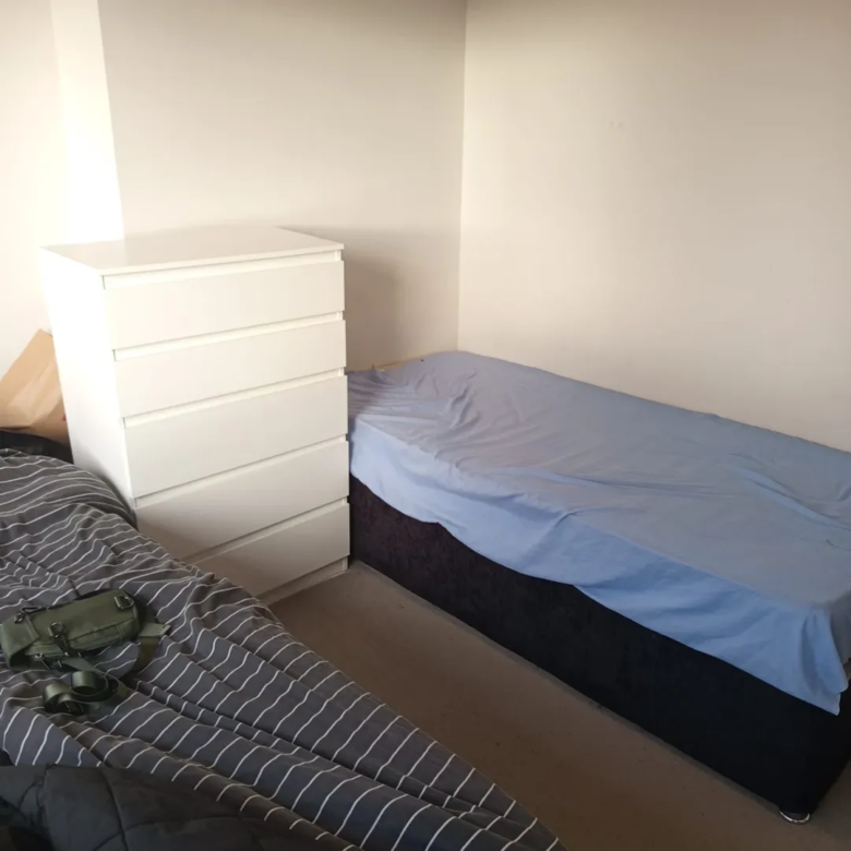 Bedroom corner with bed, white dresser, and striped bedding.