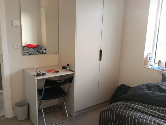 Bedroom interior with vanity, wardrobe, and bed near a window.