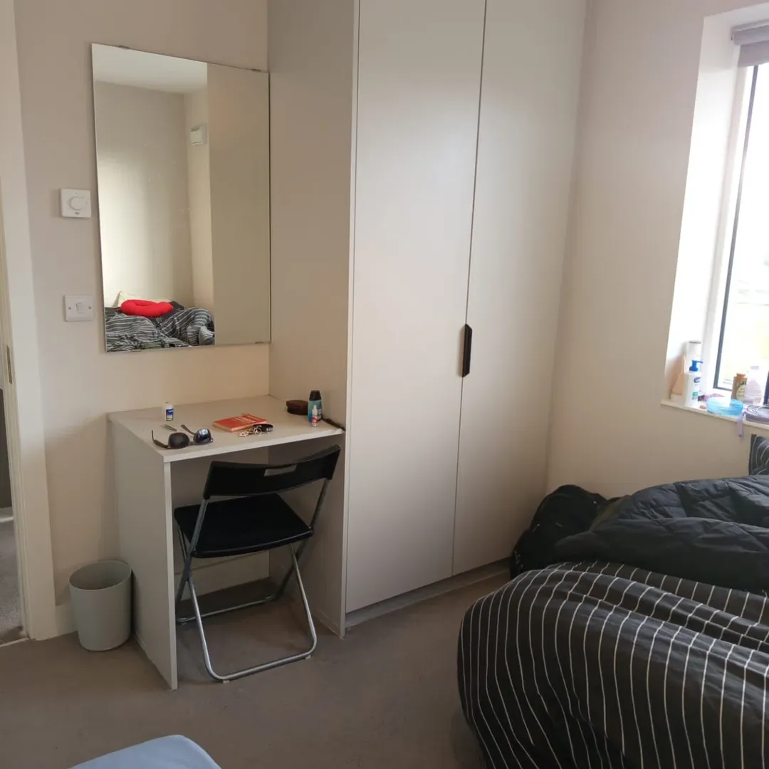 Bedroom interior with vanity, wardrobe, and bed near a window.
