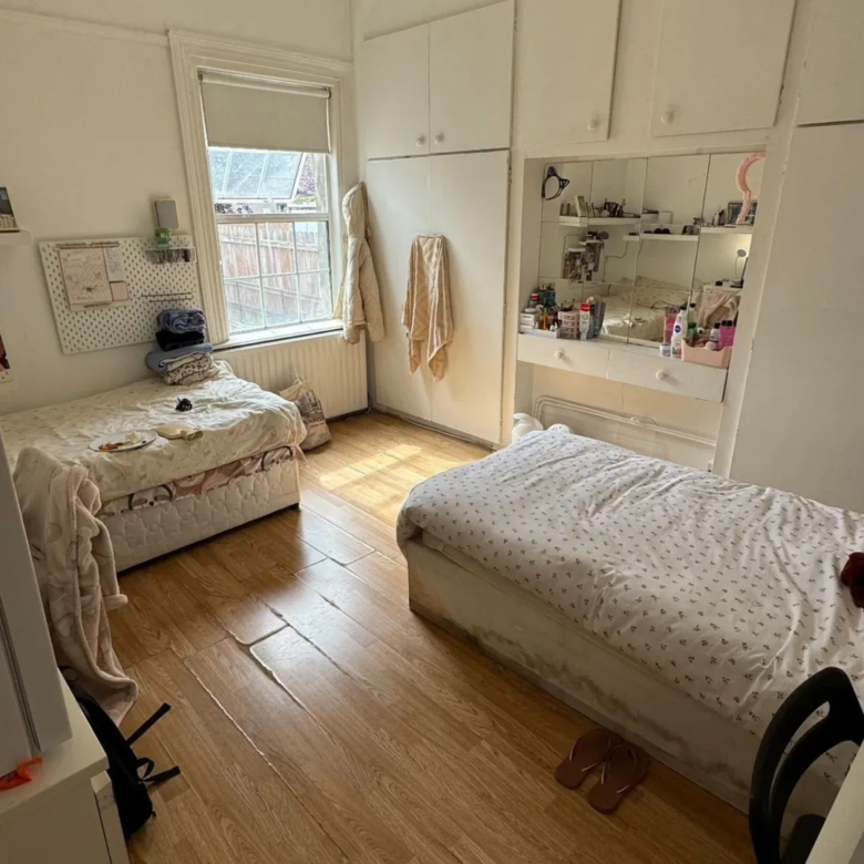 Bright bedroom with two single beds, white walls, and built-in wardrobe.