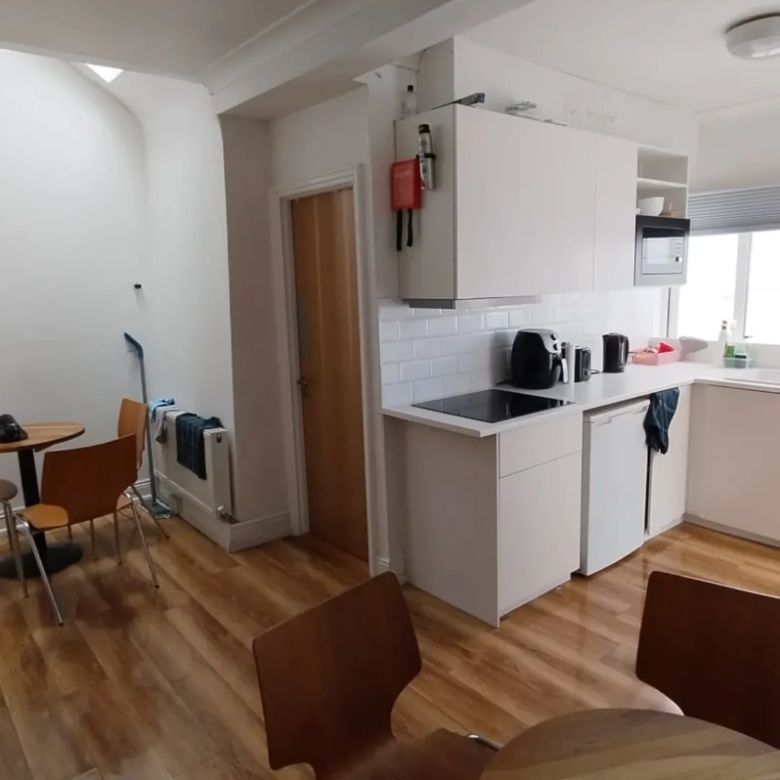 Bright kitchen with white cabinets, wood floors, and dining area.