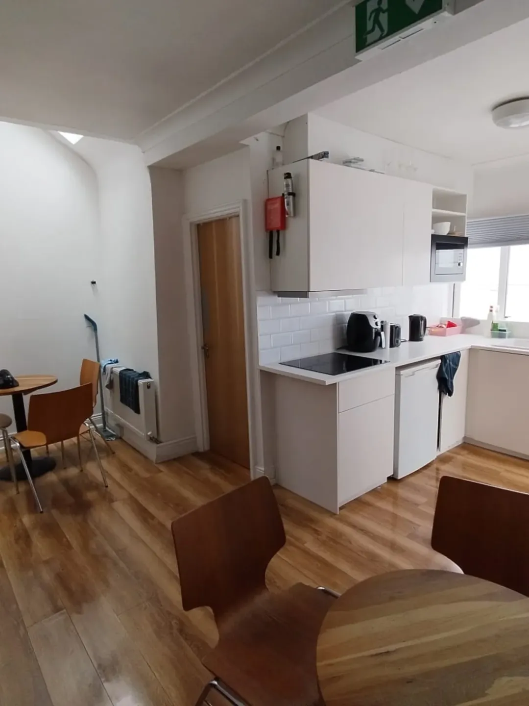 Bright kitchen with white cabinets, wood floors, and dining area.