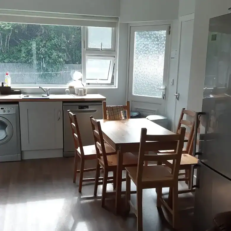Bright kitchen with wooden table and chairs, window, and appliances.