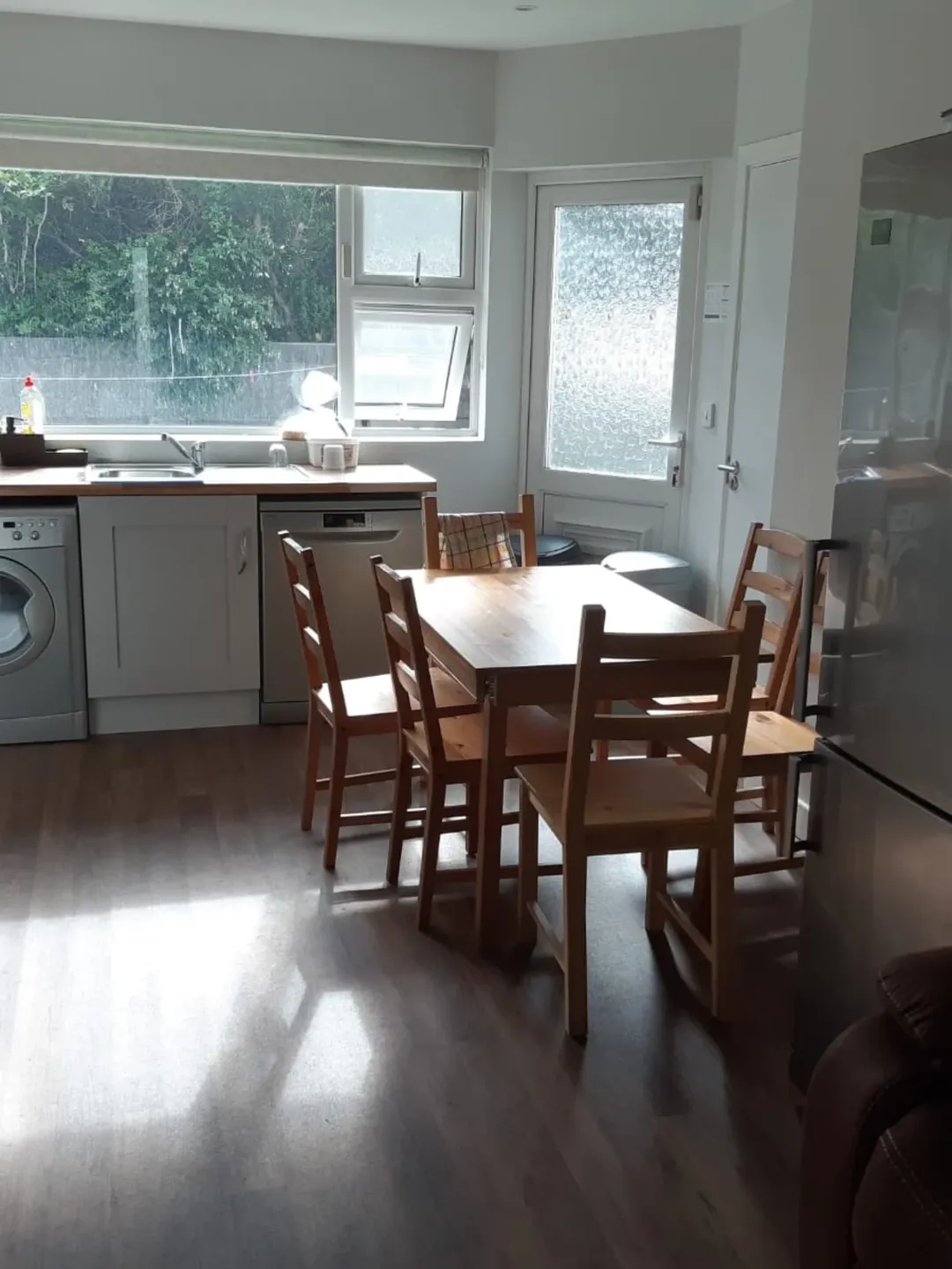 Bright kitchen with wooden table and chairs, window, and appliances.