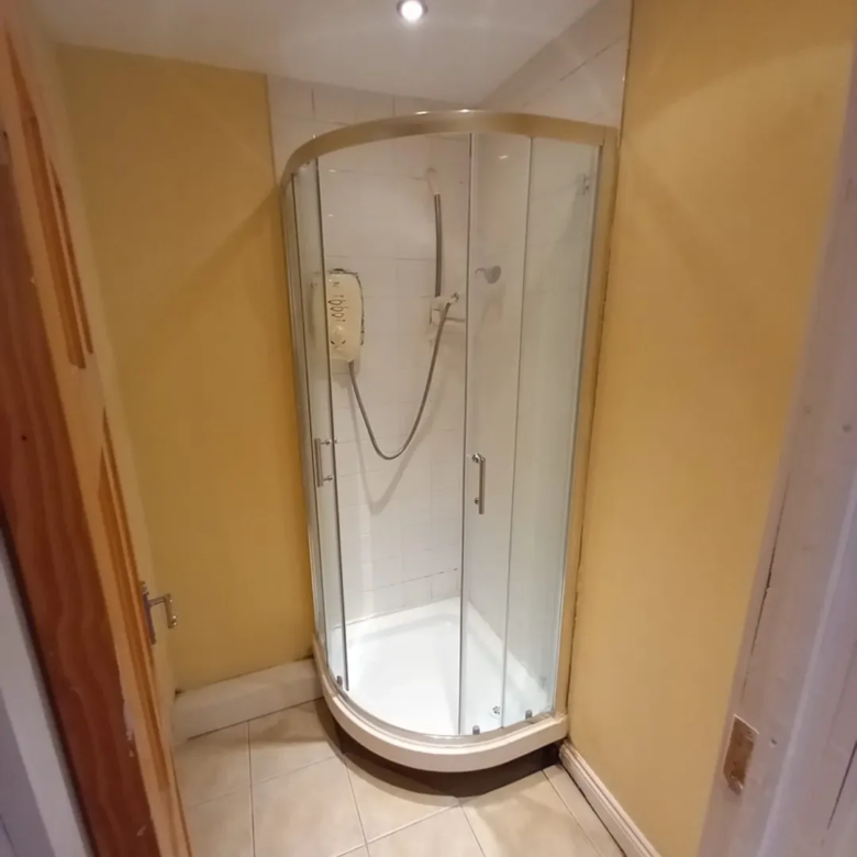 Corner shower unit with sliding doors in a bathroom setting.