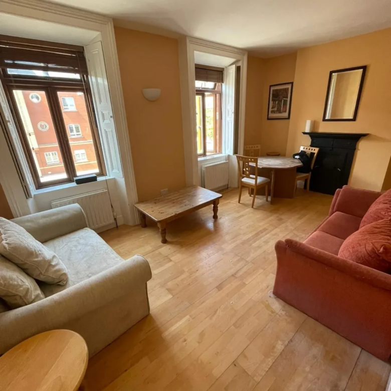 Cozy living room with sofa, coffee table, and fireplace in warm tones.