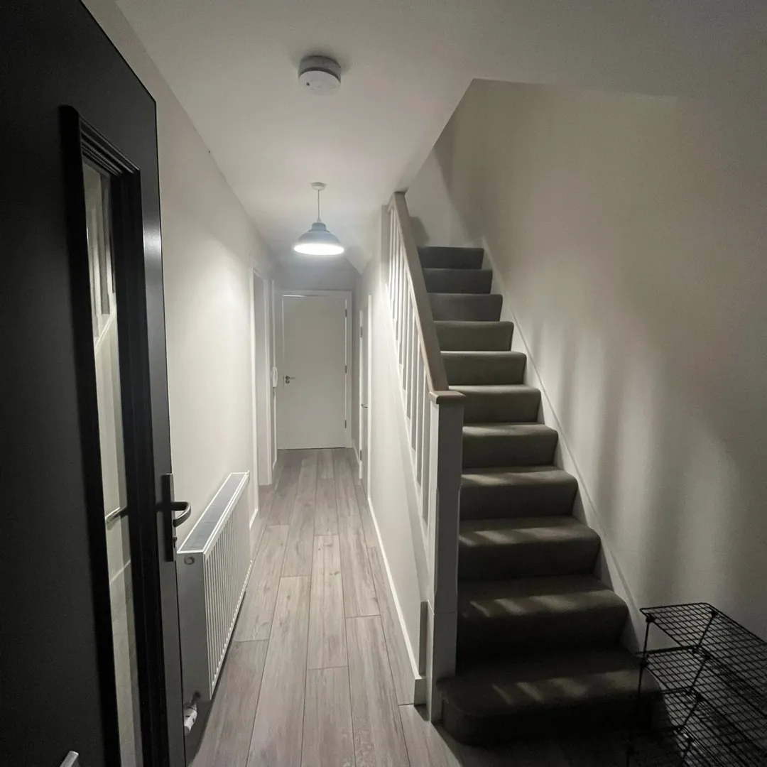 Hallway with stairs, radiator, and light wood-effect flooring.