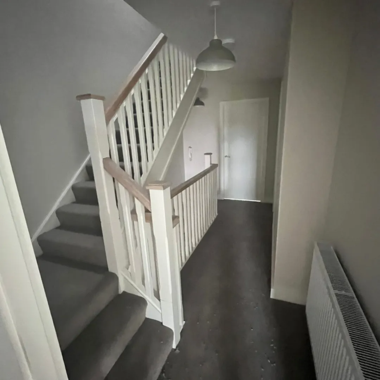 Hallway with stairs, white banister, and overhead light fixture.