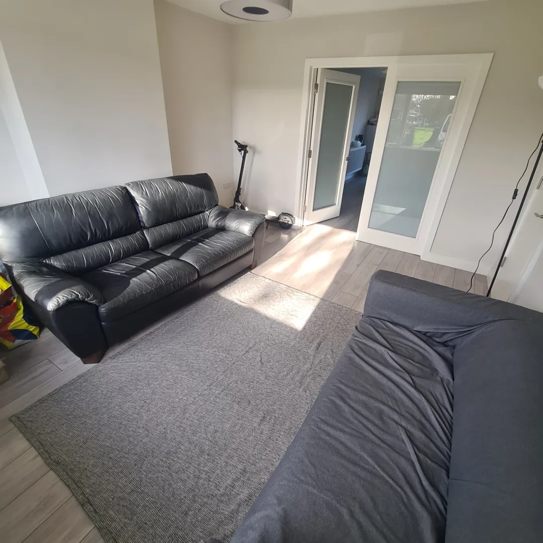 Living room with black leather sofa, gray sofa, and gray rug.