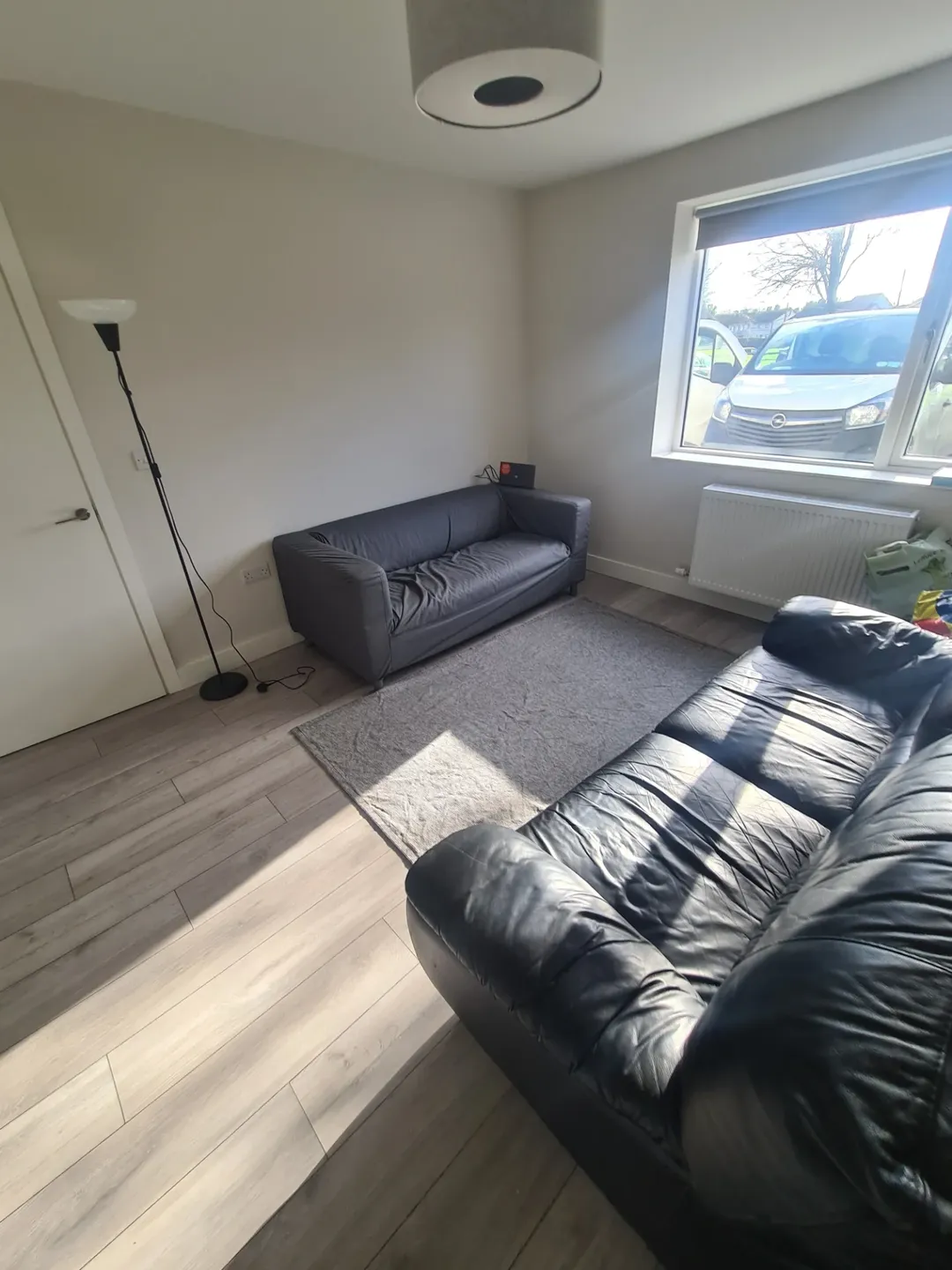 Living room with gray and black sofas, light wood floors, and natural light.