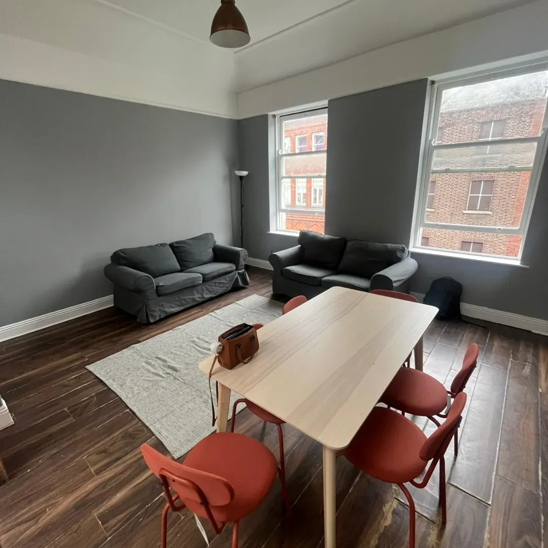 Living room with gray sofas, wooden table, red chairs, and large windows. Interior design with modern furniture.