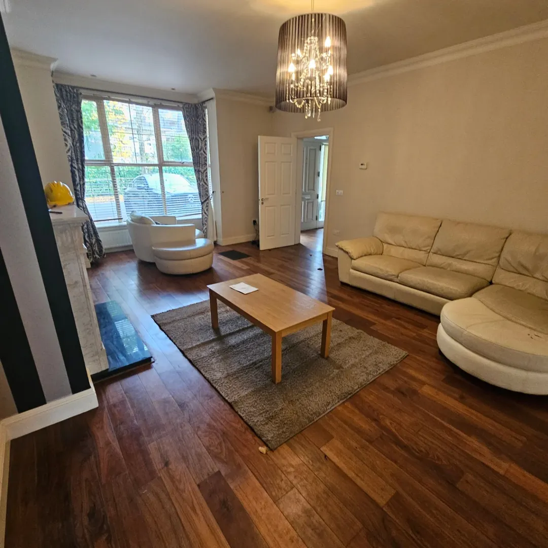 Living room with tan sofa, wood floors, chandelier, and modern fireplace.