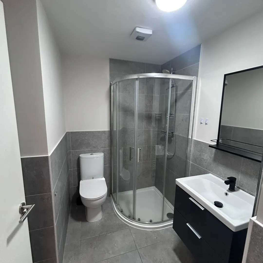 Modern Bathroom Shower Toilet Vanity Modern bathroom with shower, toilet, and vanity sink. Gray tile and clean design.