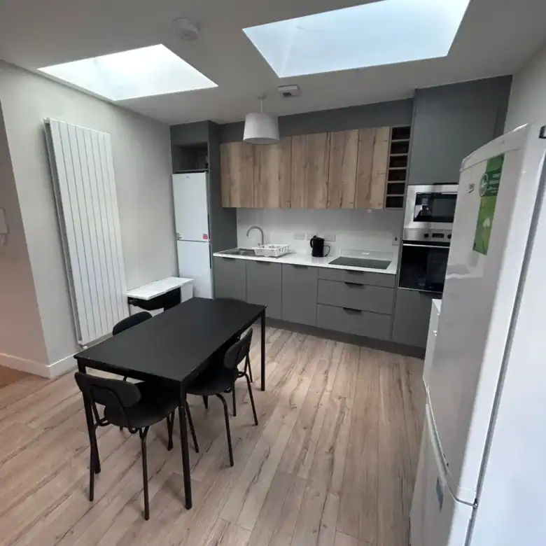 Modern kitchen with dining table, gray cabinets, and skylights.