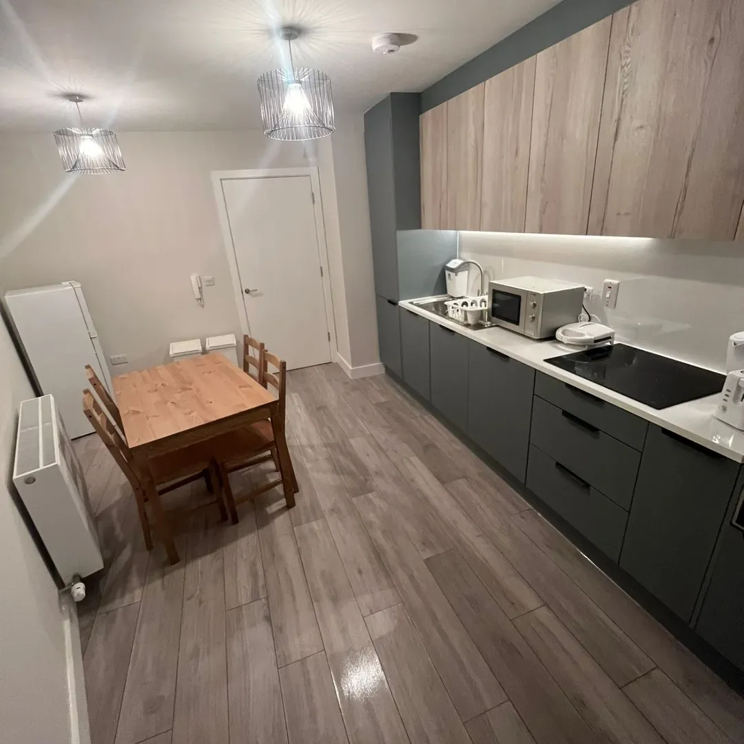 Modern kitchen with gray cabinets, wood dining table, and pendant lighting.