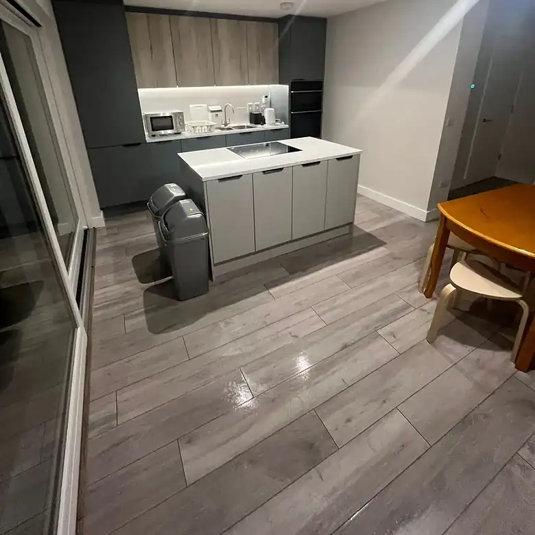 Modern kitchen with island, gray cabinets, wood floors, and dining table.