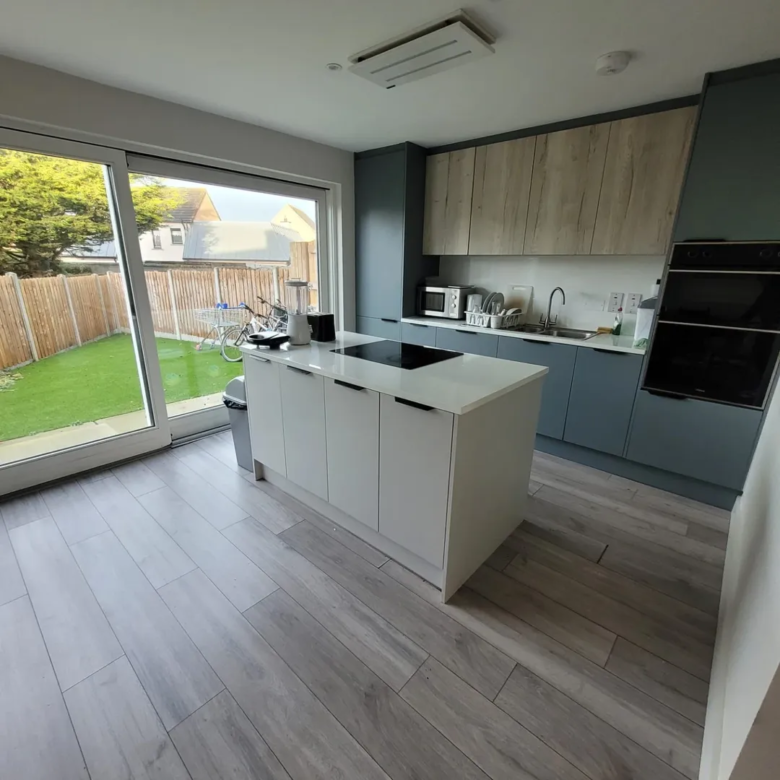Modern kitchen with island, sliding glass door, and light wood cabinets.
