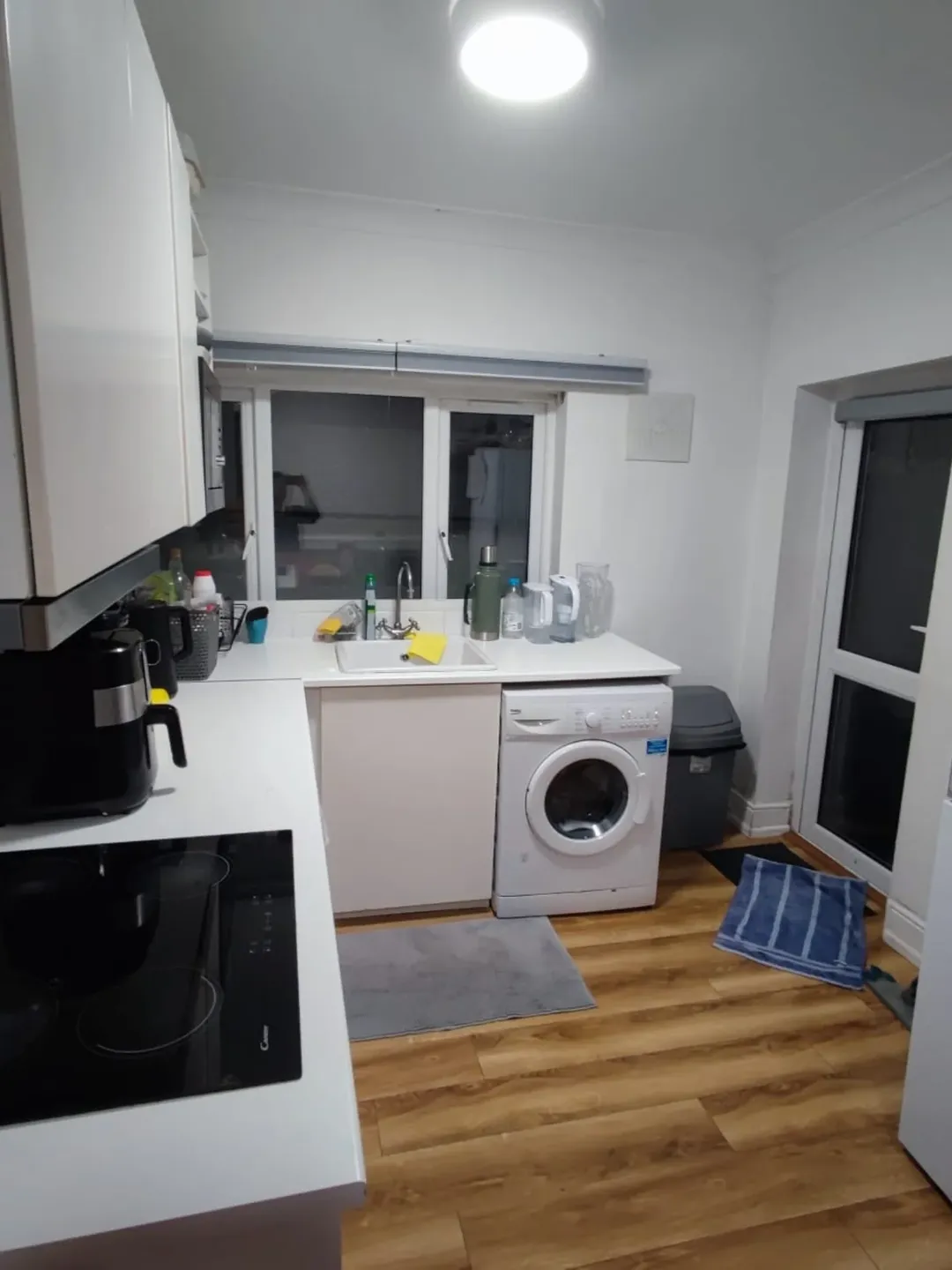 Modern kitchen with white cabinets, washing machine, and wood-look flooring.