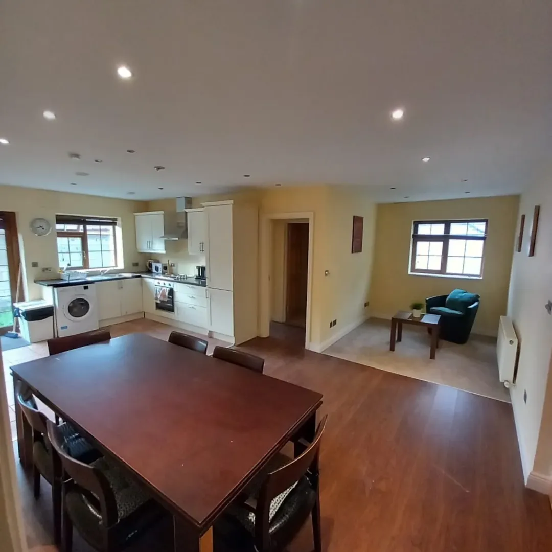 Open Plan Kitchen Dining Room Wood Floor Open-plan kitchen and dining area with wood floors, table, and armchair.