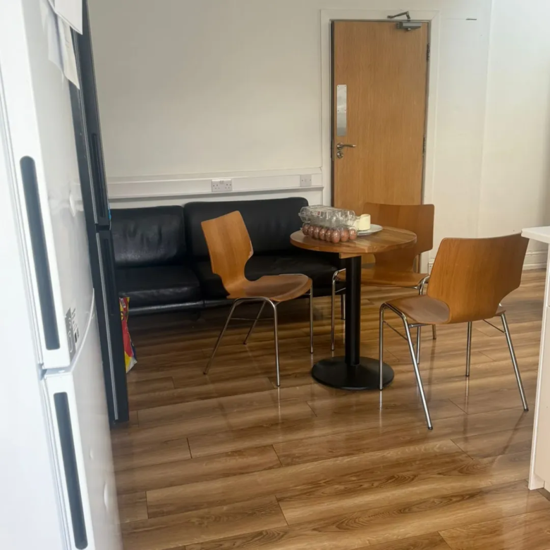 Small break room with black sofa, wooden chairs, and round table.