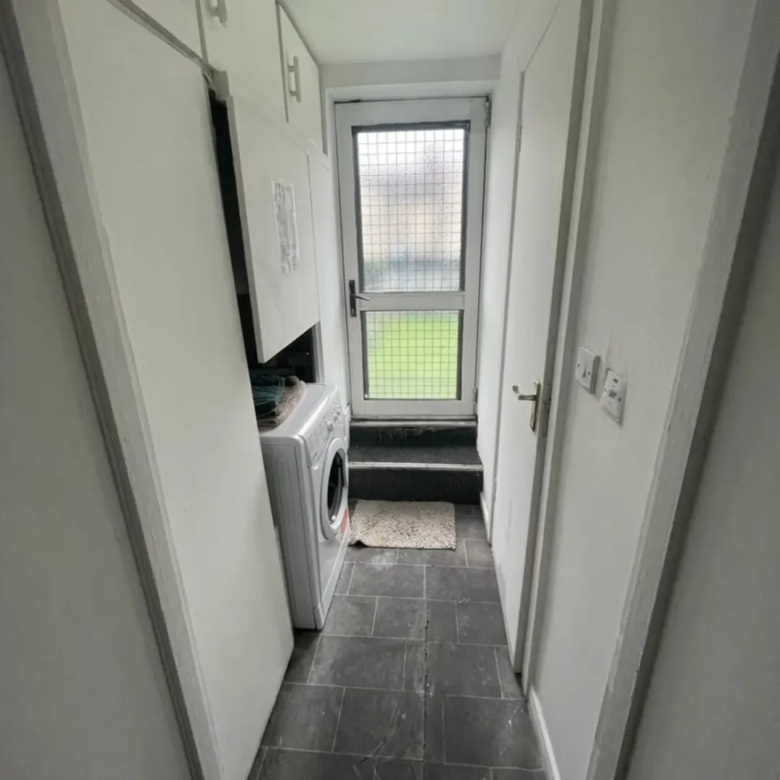 Laundry room with washing machine, cabinets, and exterior door to garden.