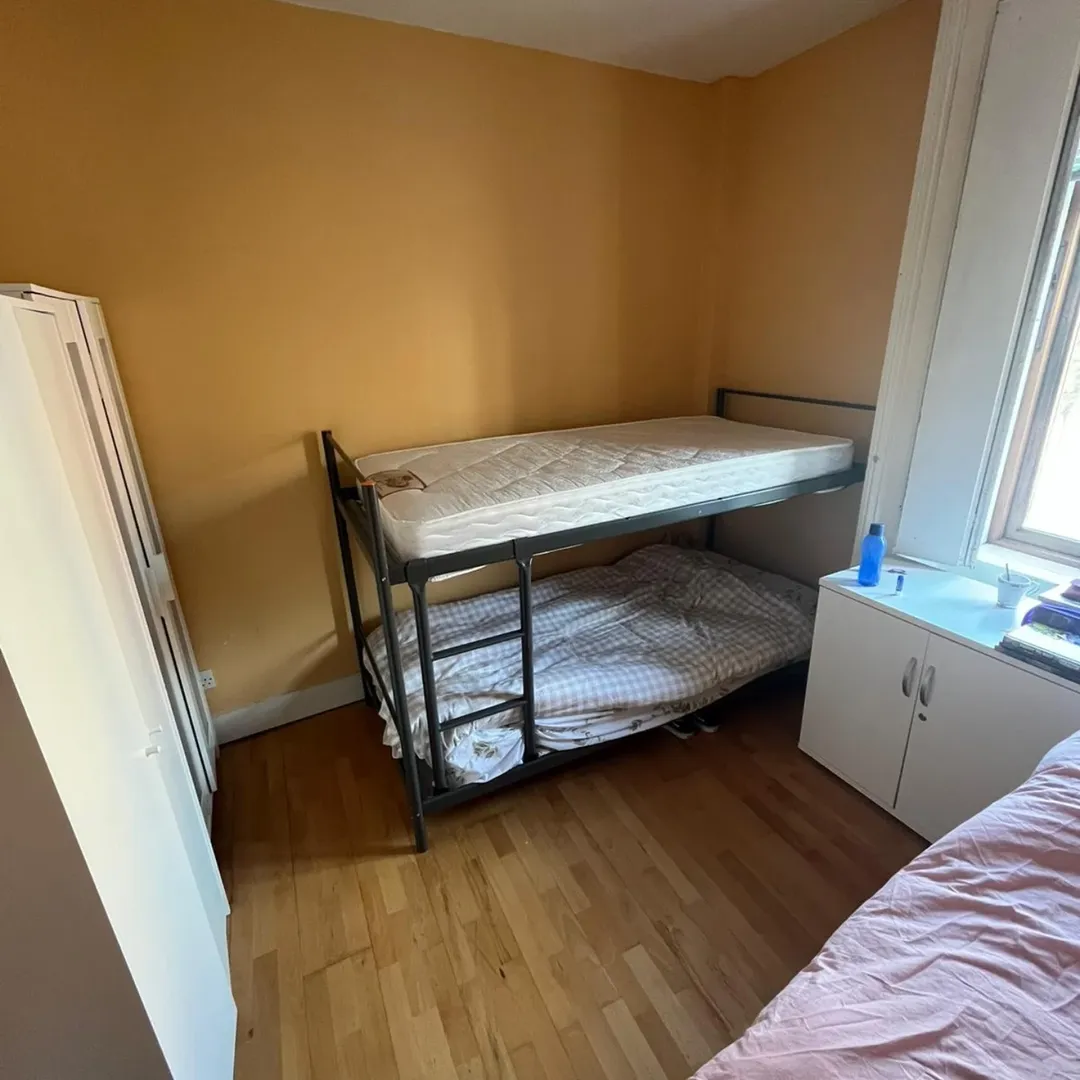 Bunk bed in small room with yellow walls and wooden floor.