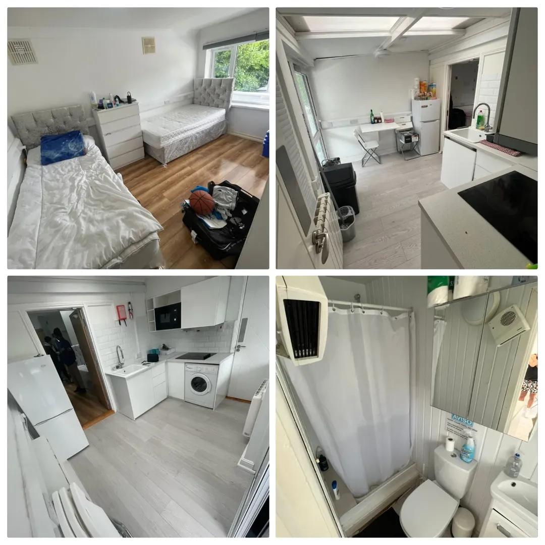 Small studio apartment interior with bed, kitchenette, and bathroom. White walls and modern design.