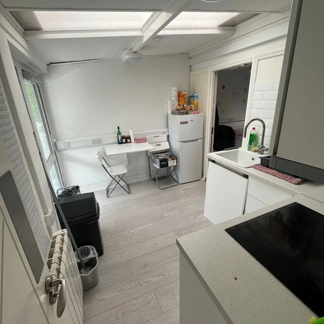 Small white kitchen with skylight, mini fridge, and dining area.