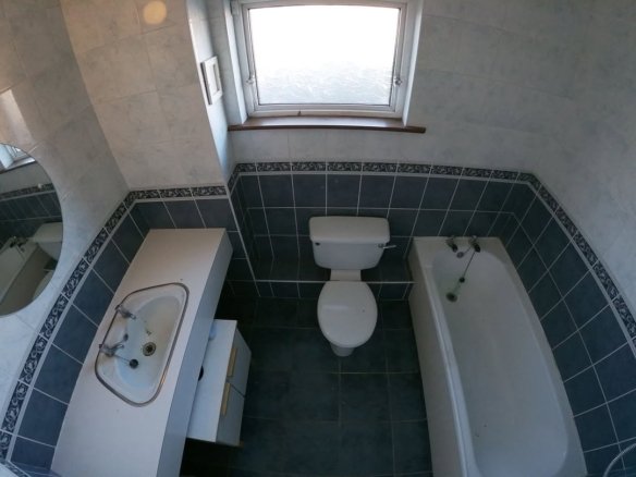 Bathroom with toilet, tub, sink, and window. Blue and white tile.