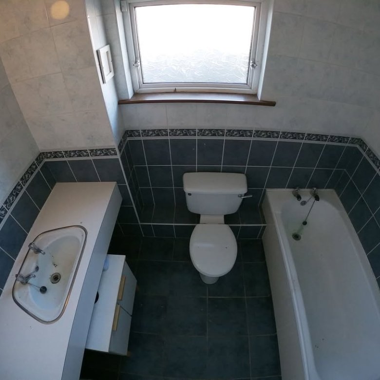 Bathroom with toilet, tub, sink, and window. Blue and white tile.