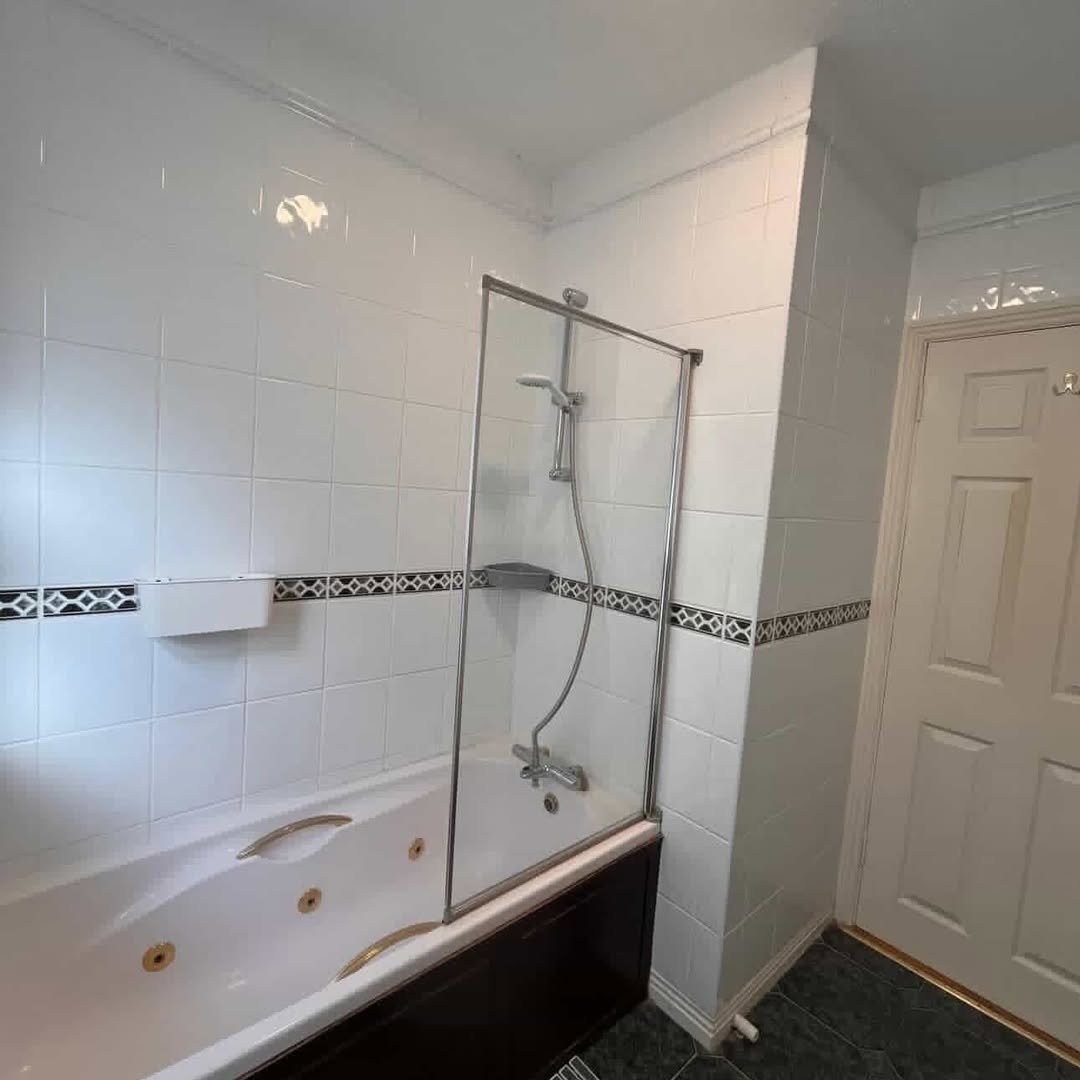 Bathroom with white tile, shower screen, and jacuzzi tub.