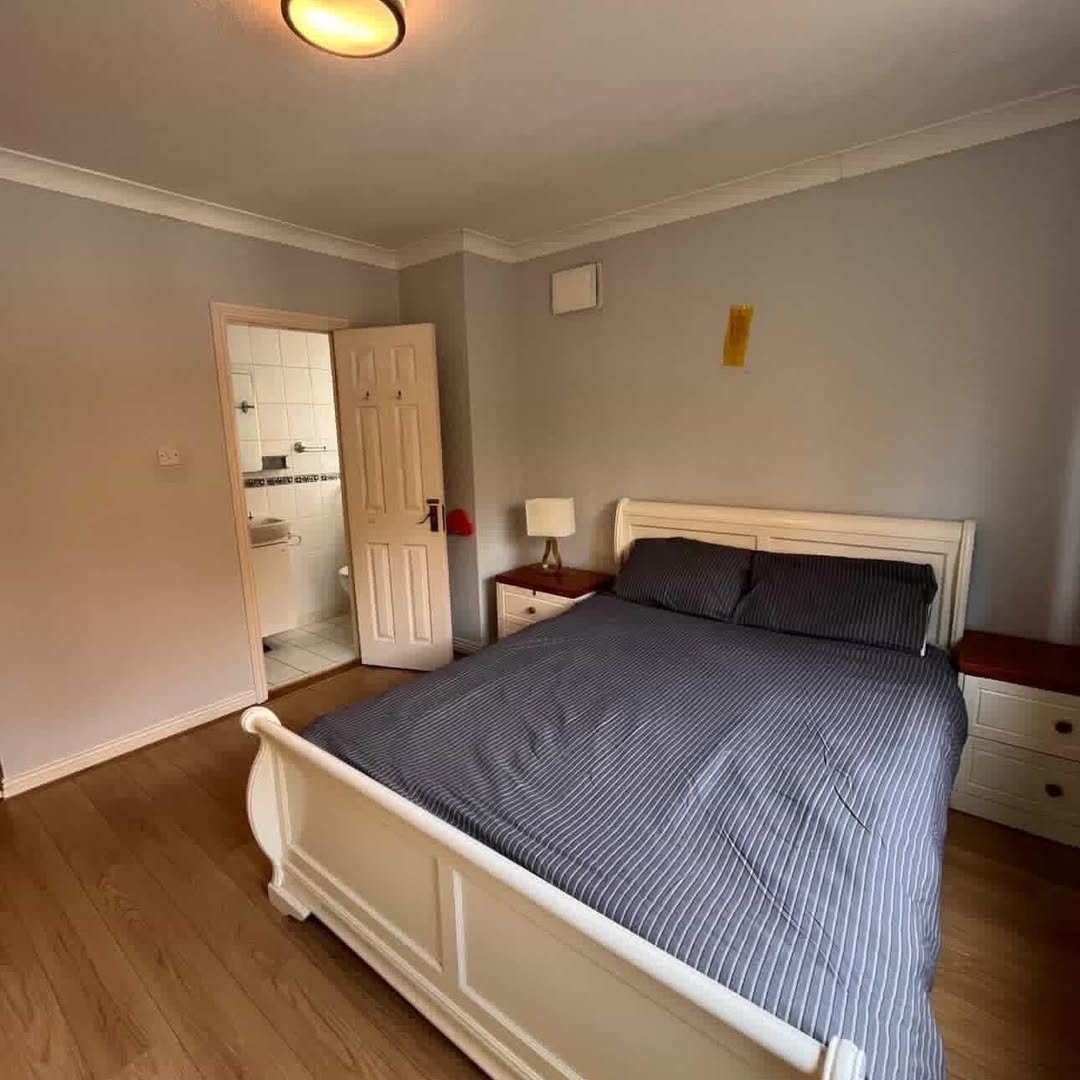 Bedroom with bed, ensuite bathroom, and wooden floors.