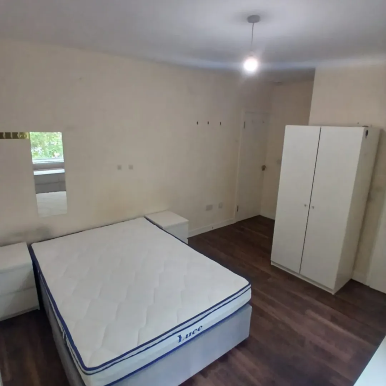 Bedroom interior: bed, nightstands, wardrobe, and dark wood flooring.