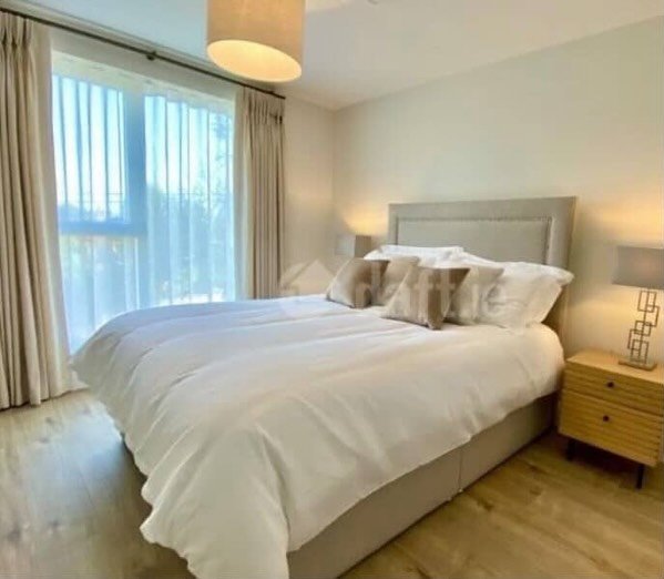 Bedroom with king bed, light walls, wood floor, and natural light from large window.