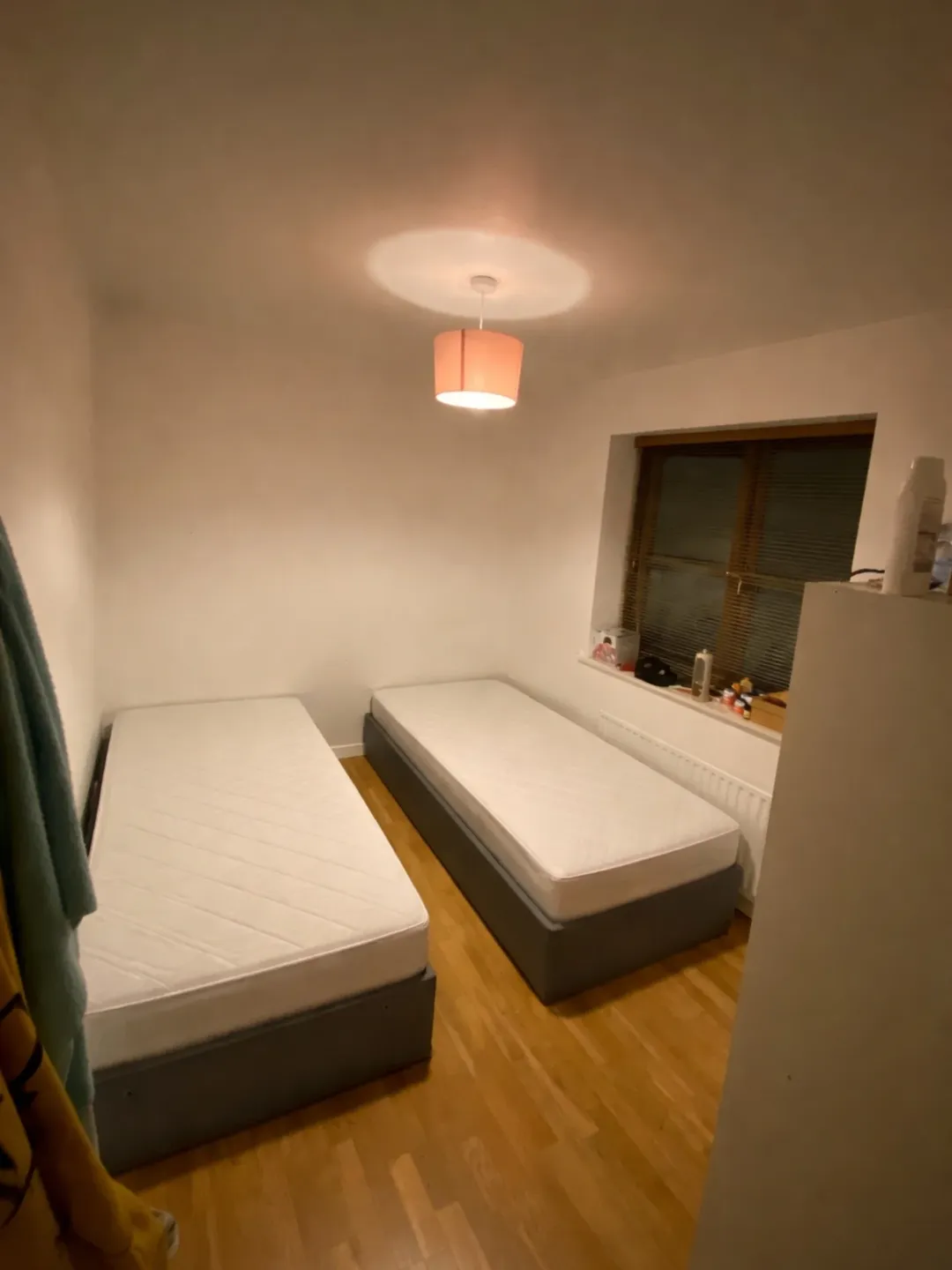 Bedroom Two Single Beds Wood Floor Cozy bedroom with two single beds, light wood floor, and warm lighting.