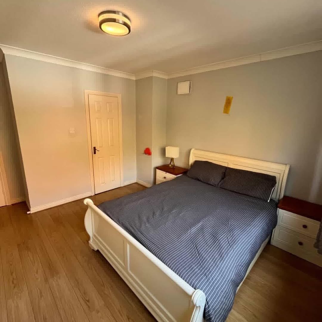 Bedroom with a white bed frame, gray walls, and wooden floors.