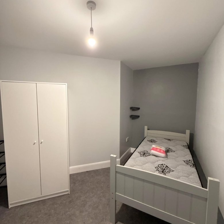 Bedroom with white bed, wardrobe, and gray walls. Simple interior.
