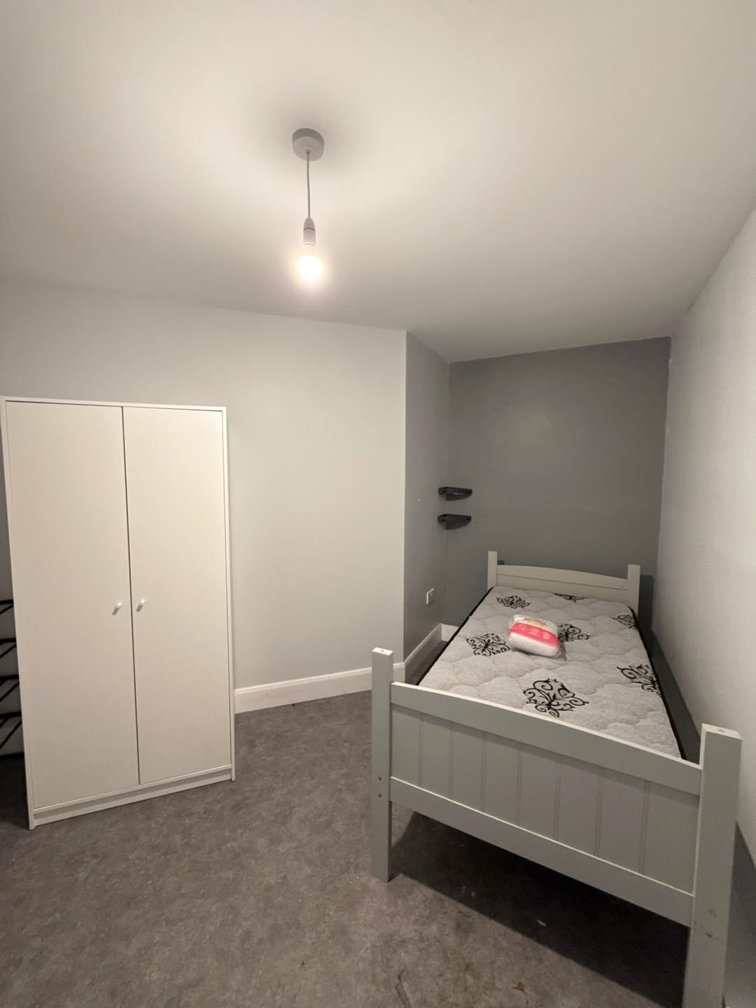 Bedroom with white bed, wardrobe, and gray walls. Simple interior.