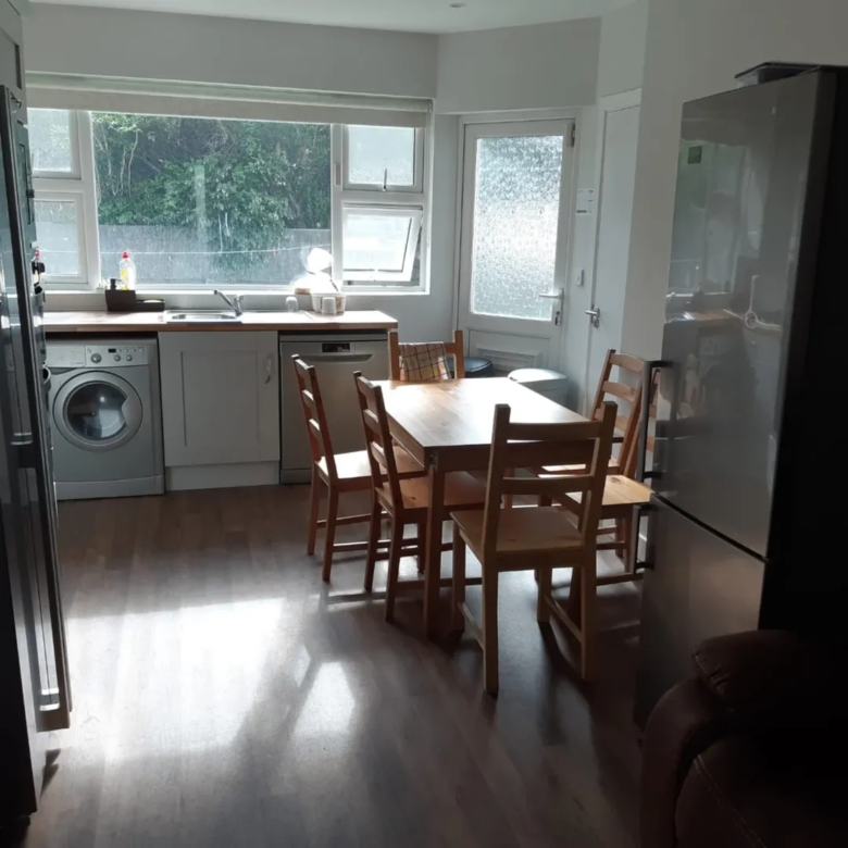 Bright kitchen with wooden dining table, chairs, and modern appliances.