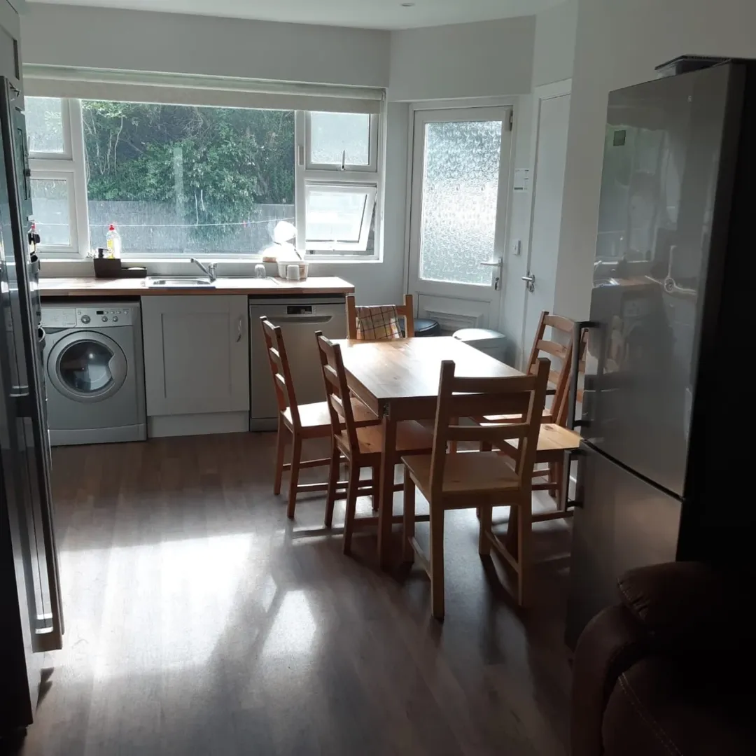 Bright kitchen with wooden dining table, chairs, and modern appliances.