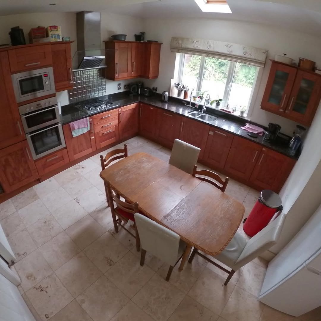 Cherry Wood Kitchen Dining Table Kitchen with cherry wood cabinets, dining table, and tile flooring under skylight.