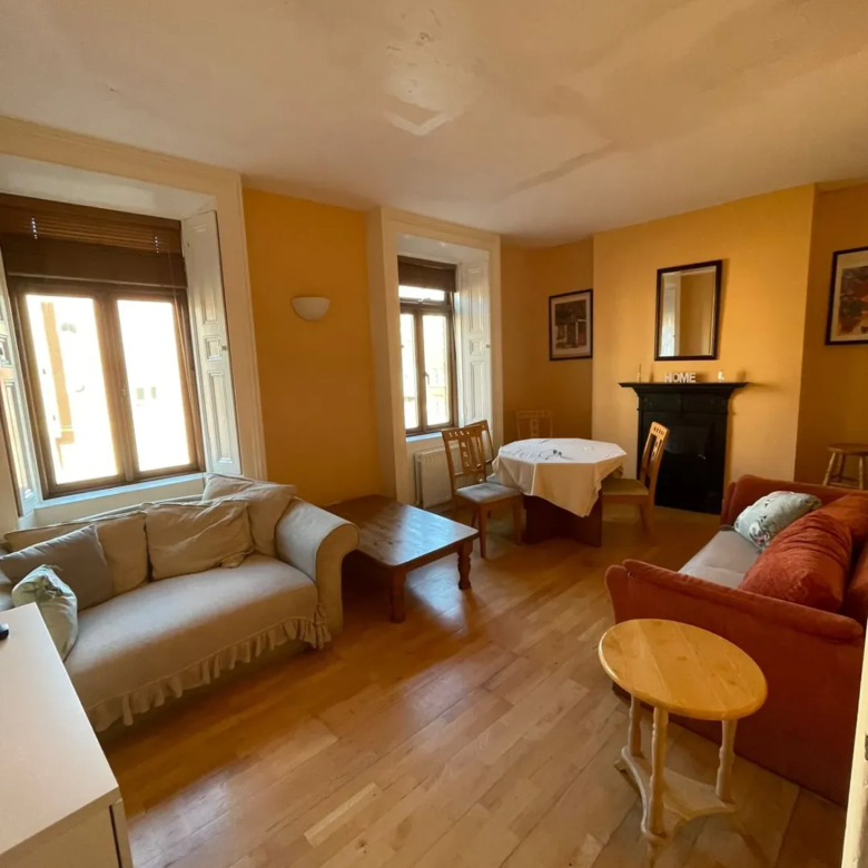 Cozy living room with sofa, round table, fireplace, and warm yellow walls.