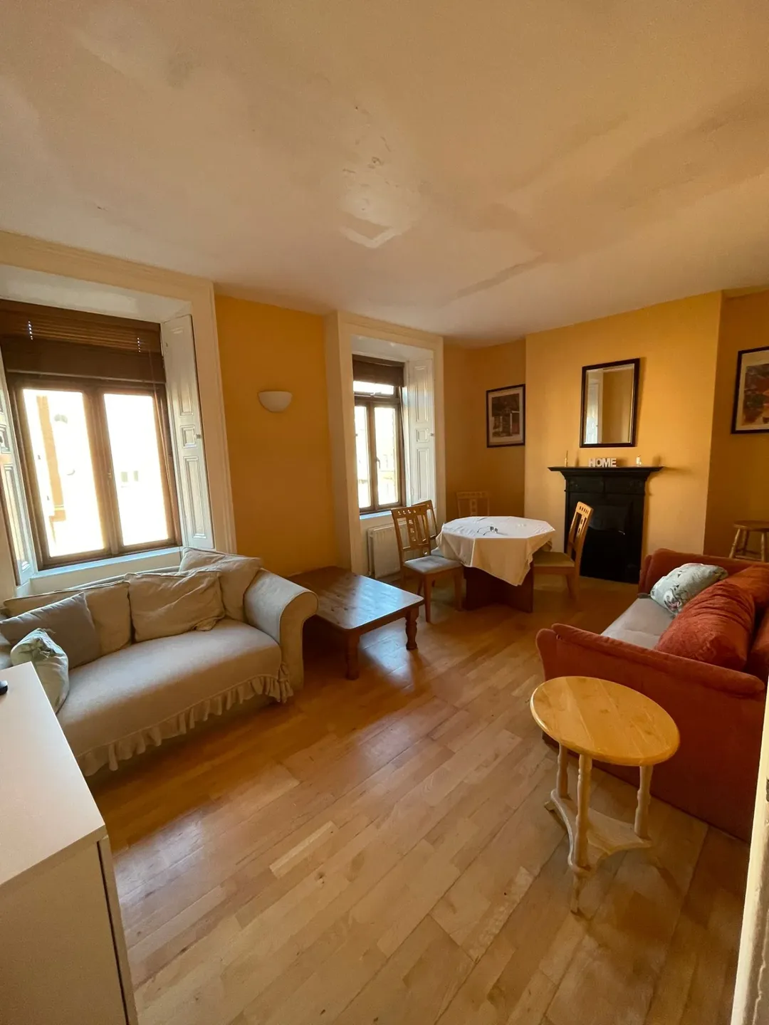 Cozy living room with sofa, round table, fireplace, and warm yellow walls.