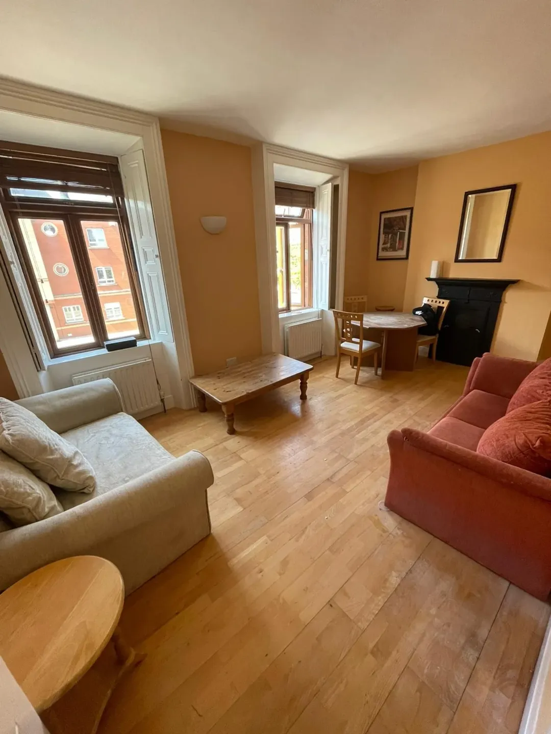 Cozy living room with sofas, wooden floors, and bright windows.