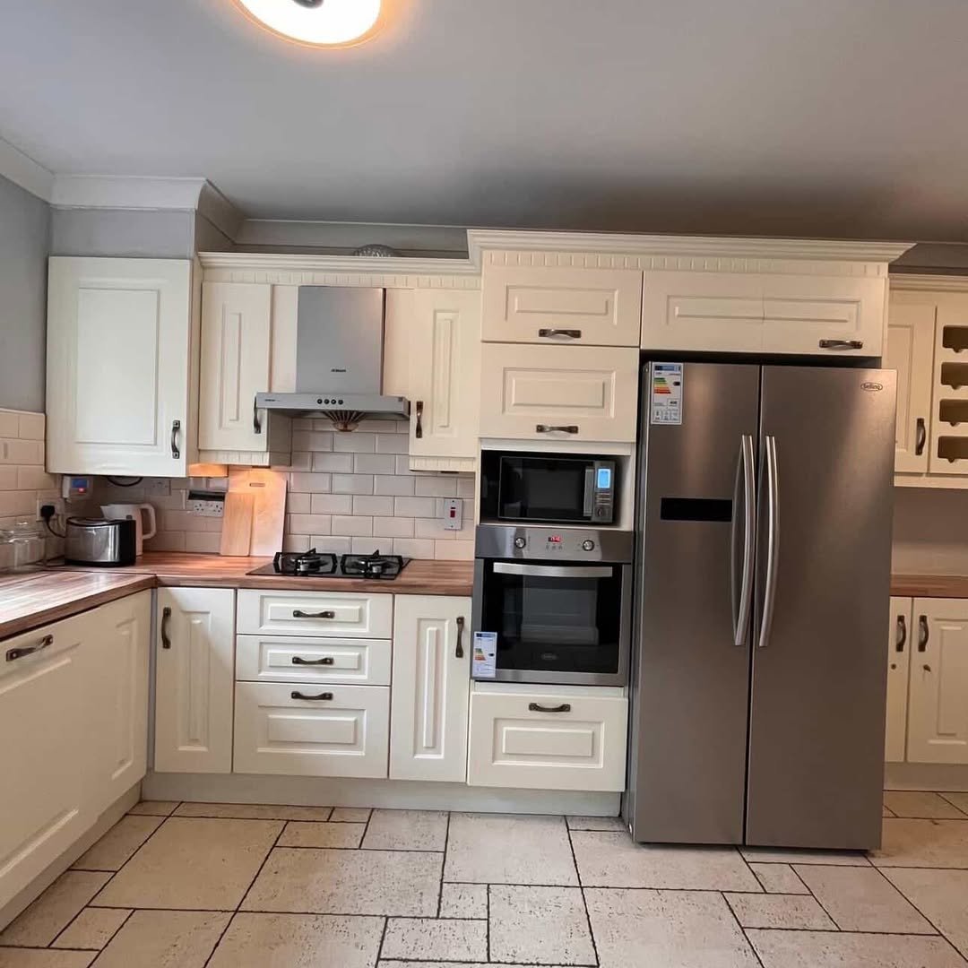 Cream kitchen with stainless steel appliances: fridge, oven, microwave, and gas hob.